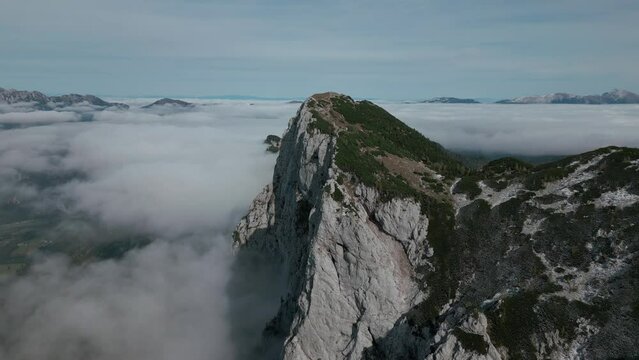 The drone takes pictures of a peak that is higher than the clouds. Drone shot of a beautiful mountain landscape. The mountain rises above the clouds.