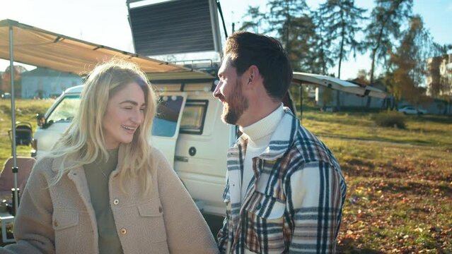 A couple sharing a joyous moment outside their camper van, immersed in laughter and conversation.
