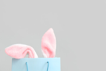 Shopping bag with fluffy Easter bunny ears on white background