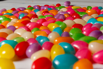 Fototapeta na wymiar Assorted colorful jelly beans candies scattered on a wooden table. Selective focus, close-up.