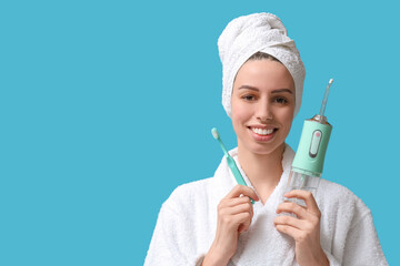 Beautiful young woman with oral irrigator and toothbrush on blue background