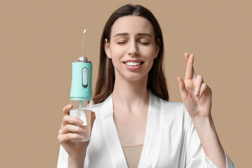 Obraz na płótnie Canvas Beautiful young woman with oral irrigator on brown background