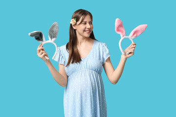 Beautiful young pregnant woman with bunny ears on blue background. Easter celebration