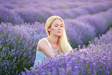 Woman walking between rows of lavender flowers and posing