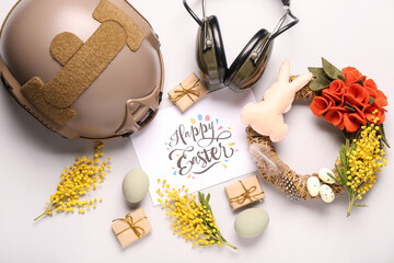 Composition with greeting card, military equipment and beautiful Easter decor on light background