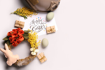 Composition with greeting card, beautiful Easter decor and military helmet on light background