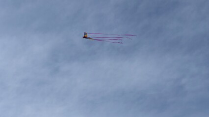 Elaborate, colorful kite flying in the sky above, with hazy clouds in background