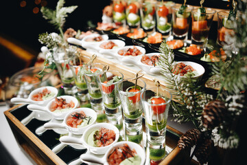 Beautifully decorated catering banquet table with different food snacks and appetizers with sandwich, caviar, fresh fruits on corporate christmas birthday party event or wedding celebration.