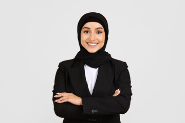 Smiling businesswoman in hijab and formal wear with crossed arms