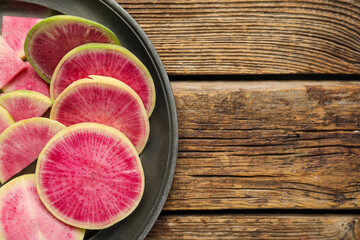 Plate with slices of ripe watermelon radishes on wooden background