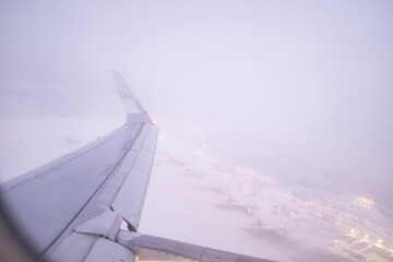 Snow storm foggy landscape airplane window scene while taking off in an airport covered in frozen...