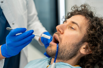 Man feeling uncomfortable during dental procedure at dentist's office.