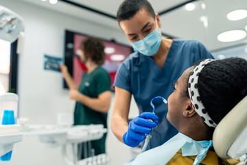 Two diverse dentists working in a modern dental clinic, treating a patient.