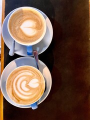 Two Cups of Artful Cappuccino on Table