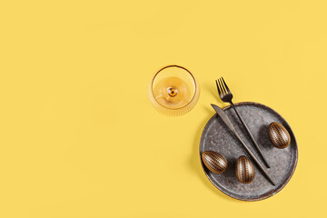 Table place setting and festive easter decor on yellow background
