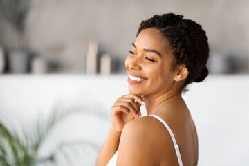 Happy young black woman wearing white tank top smiling and touching chin