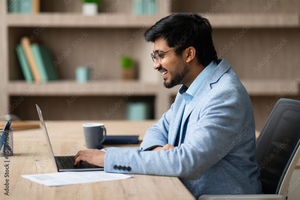 Aufkleber side view of indian businessman browsing on laptop in workspace