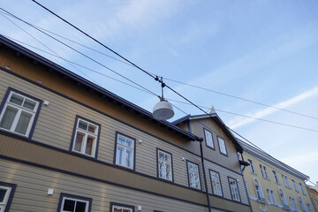 Selective focus of white street lamp, lantern. Beige building on the back. Blue sky with white...