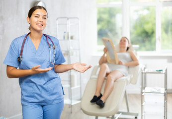 Obraz premium There is medical employee in hospital office. Unrecognizable patient sitting in chair in background. Private outpatient practice. Individual approach to treatment