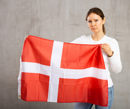 Unhappy girl holding the Danish flag in her hands. Girl is upset by the loss of her favorite team