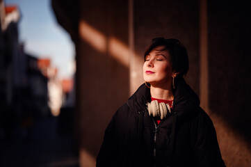 Basking in the warmth of golden sunlight, a young woman with closed eyes enjoys a peaceful moment...