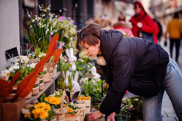 Delving into a burst of spring colors, a woman with a keen eye shops for fresh flowers at a...