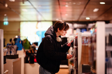 Absorbed in the variety of choices, a young woman shops attentively, her headphones signifying a...
