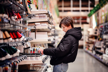 An artist intently examines a small item from the abundant shelves of an art supply store, a...