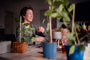 A woman's joyful laughter fills the room as she enjoys a relaxing session of indoor gardening, surrounded by lush greenery in her home