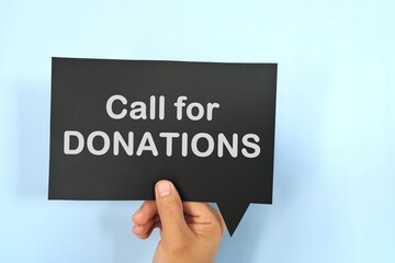 Human hand holding speech bubble with written phrase Call for Donations. Charity donations call invitation.