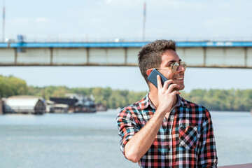 Close up portrait of cheerful mature man using mobilephone and laughing. Handsome hipster talking on the phone.