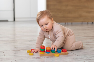 Cute adorable baby play with wooden educational toys at home. Montessori materials for child development. Selective focus