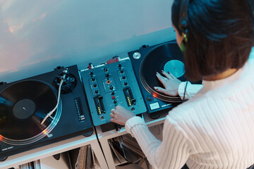 A woman DJ in action, using a turntable and mixer to play music.