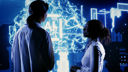 Licensed employees looking at hologram of artificial intelligence human brain simulation. Trained...