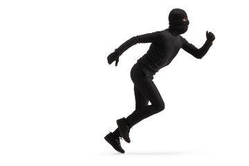 Fototapeta na wymiar Full length profile shot of a thief in black clothes and balaclava running