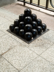 Pile of black color well preserved cannon balls. Old time warfare craft. Cost of war and materials for destruction and conquest. Military equipment and supply theme.