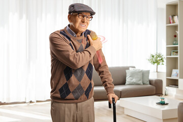 Elderly man in pain holding his shoulder at home