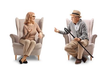 Elderly man sitting in an armchair and talking to a middle aged woman