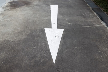 A large white arrow painted on the asphalt points downward, dictating the direction of movement