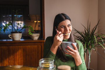 A young woman eating corn flakes for breakfast in the morning in her apartment	