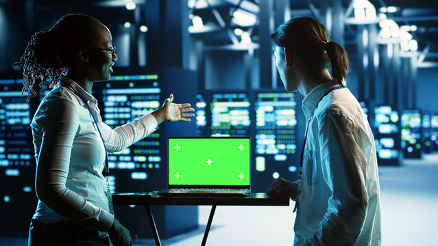 African american admin and colleague using mockup laptop to implement artificial intelligence parallel processing. Experts work on chroma key device enabling AI systems to do machine learning