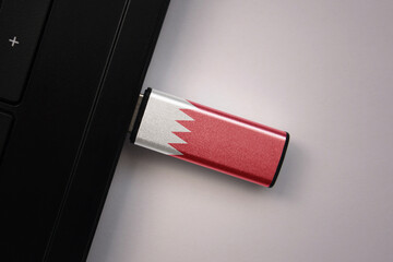 usb flash drive in notebook computer with the national flag of bahrain on gray background.