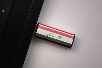 usb flash drive in notebook computer with the national flag of iraq on gray background.
