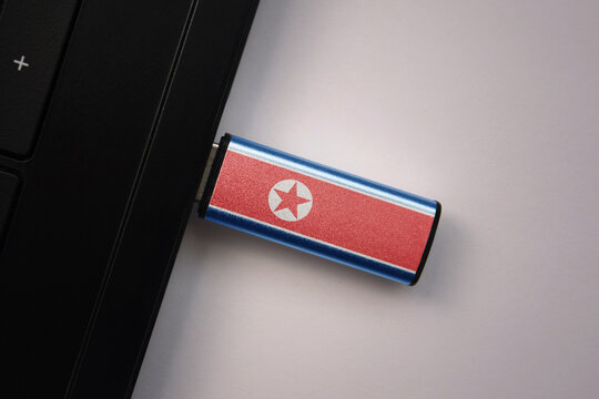 usb flash drive in notebook computer with the national flag of north korea on gray background.