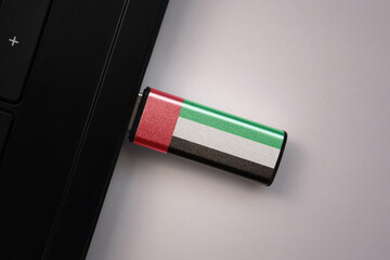 usb flash drive in notebook computer with the national flag of united arab emirates on gray...