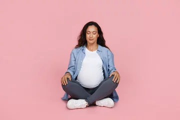 Poster Peaceful pregnant woman sitting on floor, meditating © Prostock-studio