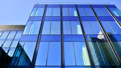 Modern office building with glass facade. Transparent glass wall of office building. Reflection of the blue sky on the facade of the building.