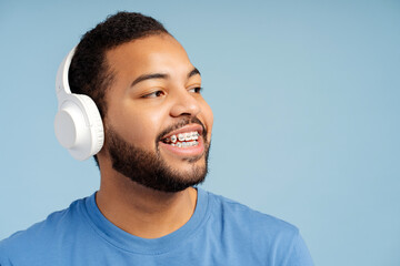 Portrait of smiling attractive man with dental braces wearing headphones isolated