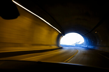 Movimiento rápido. Transitando un túnel curvo en alta velocidad desde un automóvil. Luces ámbar barridas por la rapidez del movimiento. Luz al final del camino. Carretera mexicana.