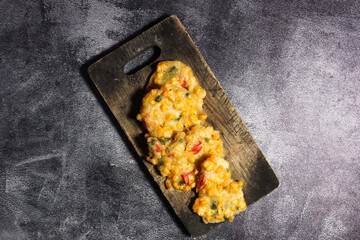 Top view of Bakwan Jagung or Dadar Jagung or Dadar Jagung . Indonesian snack made from corn and flour. Served on a wooden plate. 